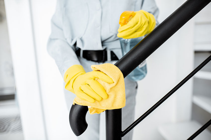 Woman cleaning stair railings at home