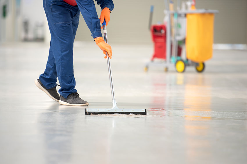 The man in the repairman is holding a mop in a white suit, clean