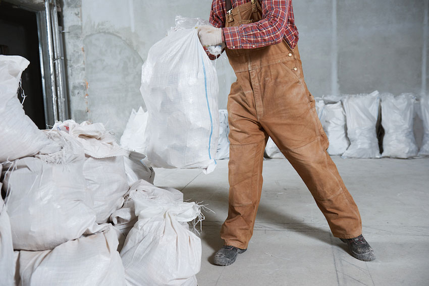Worker collecting construction waste in bag